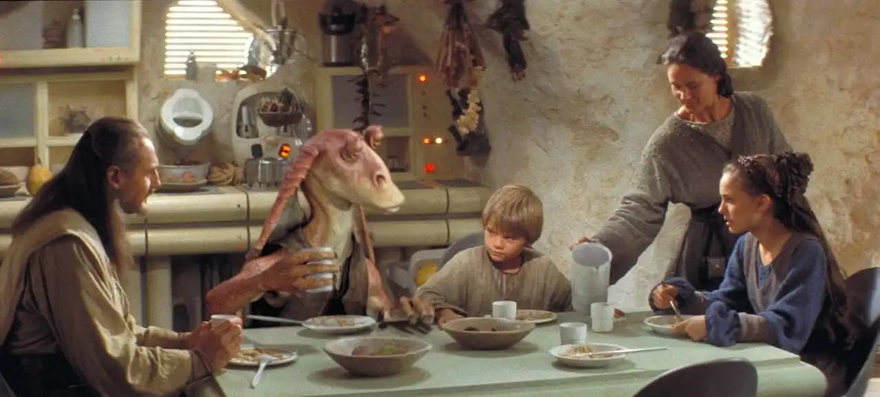 Image of Anakin enjoying a meal as a child with friends and family.